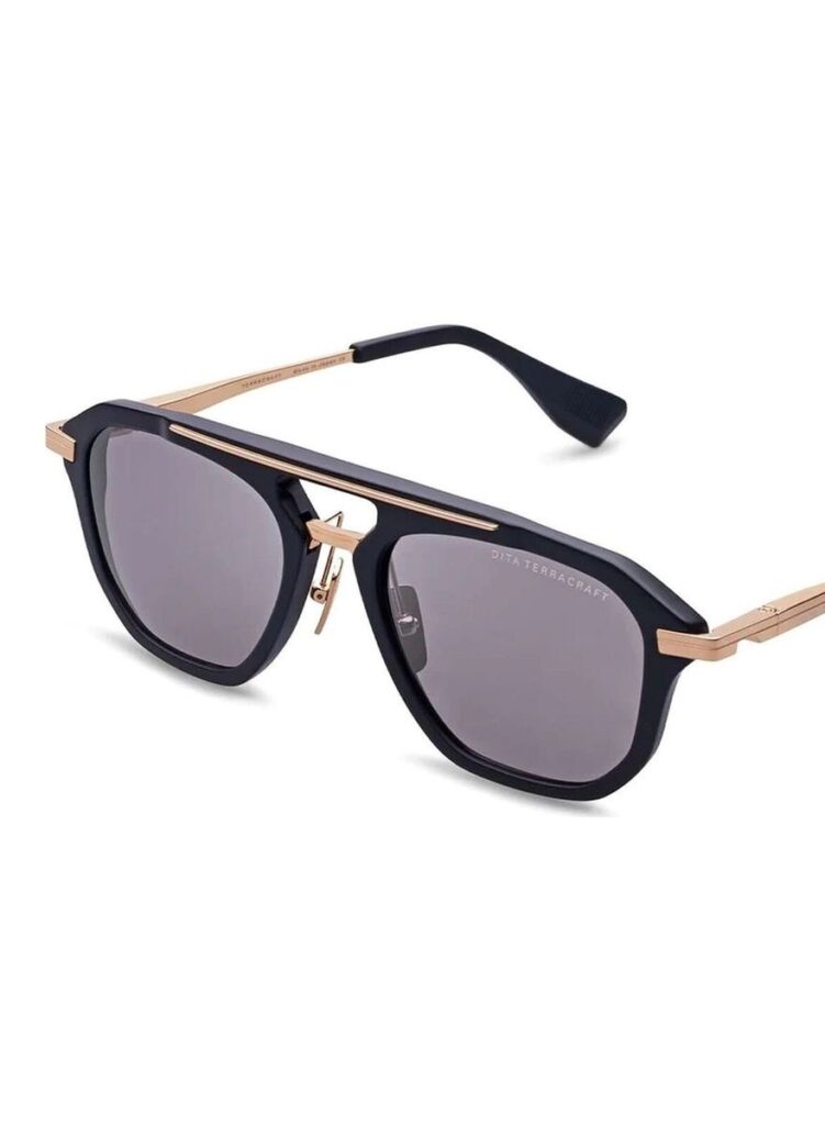 Stylish black sunglasses with a geometric frame, gold detailing on the temples, and dark lenses. The design features a sleek, modern look with a distinctive bridge piece.