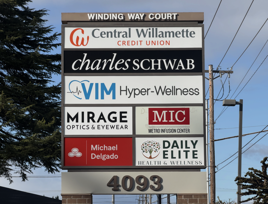 A business sign for Winding Way Court lists Central Willamette Credit Union, Charles Schwab, VIM Hyper-Wellness, Mirage Optics & Eyewear, MIC Metro Infusion Center, Michael Delgado, and Daily Elite Health & Wellness.